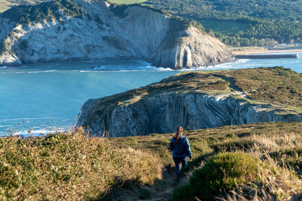 Young woman hikes in a peaceful, mountainous landscape, overlooking the serene ocean